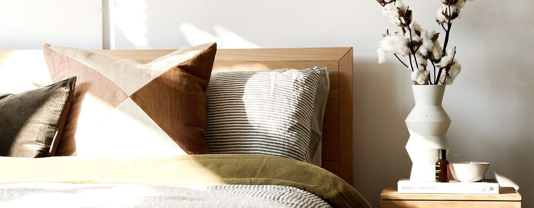 neatly made bed and decorated side table in naturally lit bedroom